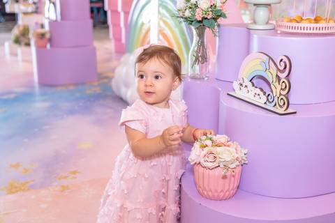 Fase de primeiros passos e descobertas do bebê. Cecília se divertindo ao lado da mesa de aniversário decorada.'