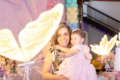 Registro afetivo de vó e filha em Brasília. Bonny e Cecília posando com decoração iluminada de borboleta.'