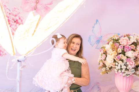 Momentos de carinho na festa de um ano da Cecília. Convidada sorrindo com a aniversariante no colo em Brasília.'
