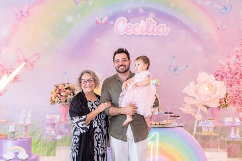 Retrato de família com a aniversariante de um ano. bisavó, tio e Cecília sorrindo em momento de parabéns.'