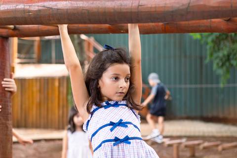 Coordenação motora e desenvolvimento físico saudável. Maria Teresa brincando nos obstáculos de madeira no parque.'