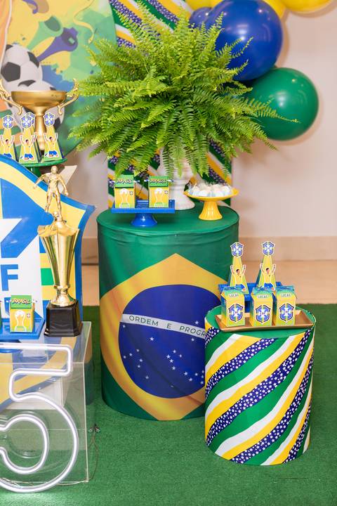Elementos de decoração de festa de 5 anos no DF. Cilindros e arranjos temáticos do Brasil.'