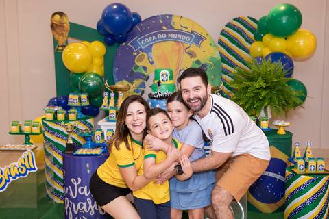 Conexão materna e afeto em festa infantil. Fernanda rodeada pelo carinho dos filhos Lucas e Olívia.'