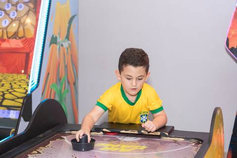 Concentração e jogos recreativos na infância. Lucas se divertindo no brinquedo eletrônico em sua festa.'