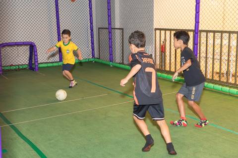 Partida de futebol infantil em festa de aniversário. Recreação saudável entre amigos no buffet.'