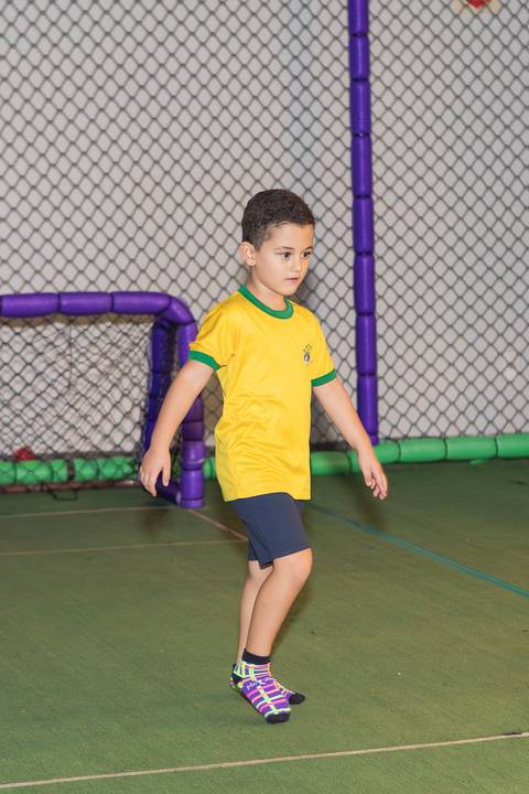 Energia e movimento na comemoração de 5 anos. Meninos jogando bola na área de esportes do evento.'