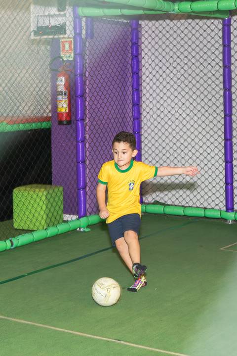 O aniversariante Lucas mostrando sua paixão por futebol em campo durante a festa.'