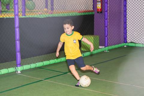 Preservação da imagem e momentos de movimento na infância. Criança se divertindo de forma livre na quadra de esportes.'