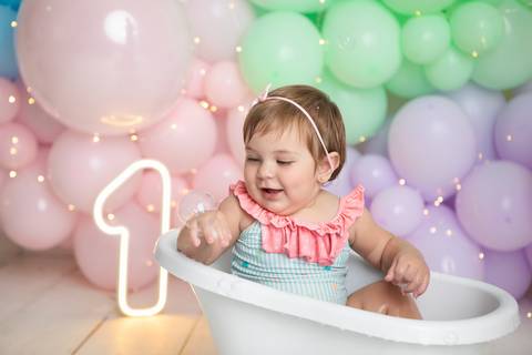 Momentos de lazer e bem-estar do bebê em Brasília - DF. Helena sorridente no banho pós-bolo.'