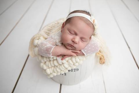 Ensaio newborn seguro da bebê Laura em Brasília. Fotografia de recém-nascido em tons de rosa e lilás na região do Jardim Botânico e Lago Sul, DF. Fotógrafa Letícia Franco.'