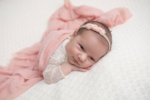 Ensaio newborn seguro da bebê Laura em Brasília. Fotografia de recém-nascido em tons de rosa e lilás na região do Jardim Botânico e Lago Sul, DF. Fotógrafa Letícia Franco.'