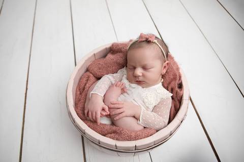 Ensaio newborn seguro da bebê Laura em Brasília. Fotografia de recém-nascido em tons de rosa e lilás na região do Jardim Botânico e Lago Sul, DF. Fotógrafa Letícia Franco.'