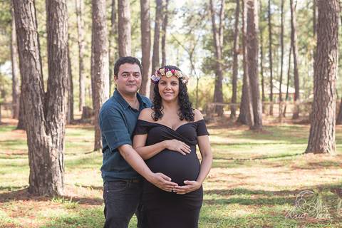 pinheiros e gestante no jardim botanico com vestido preto e coroa de flores brasilia df grávida book com papai marido mão na barriga'