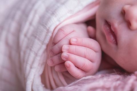 newborn recém nascido nascida baby bebê pequeno poucos dias novo nascimento book família foto pacotinho wrap charutinho rosa pelo rosa falso flokati segurando coração macro detalhe cílio brasília df mãos boca nariz'