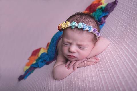 bebe recem nascido newborn book preço valor brasilia df pose mão no queixo mãozinha queixinho barriga pra baixo fundo rosa com branco e headband faixa cabelo arco-iris rainbow baby bebe tempestade felicidade paninho wrap branco por cima arco iris colorido'