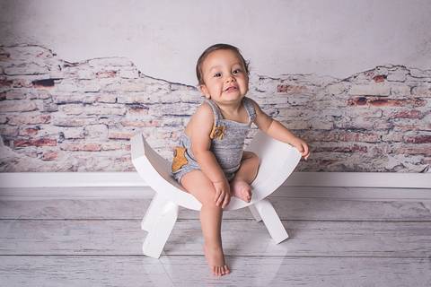 acompanhamento bebe book preço valor investimento brasilia df noroeste 10 meses fundo muro descascado vitor vestido macacão cinza prop cadeira banco curvado sorrindo mão no joelho sentado'