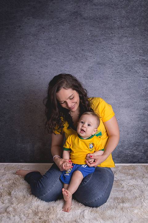bebe book ensaio acompanhamento 06 07 meses fundo azul chão madeira caixinha de coração roupa azul de capuz sorrindo bebe sério tapete com a mamãe jeans e blusa branca irmã uniforme seleção brasileira futebol copa do mundo'