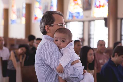 pai segurando bebê no batismo batizado na igreja nossa senhora de fatima brasilia df registrado pela fotógrafa Letícia Leticia Franco em brasília brasilia df'