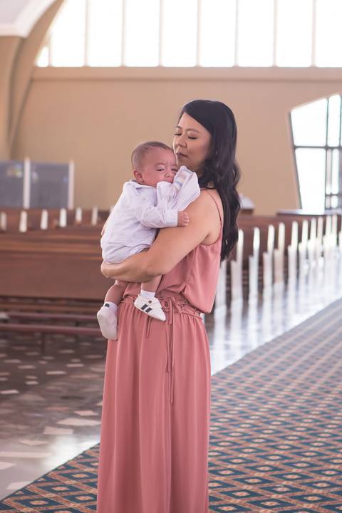 mãe segurando e acalmando bebe durante o batizado nossa senhora de fatima brasilia registrado pela fotógrafa Letícia Leticia Franco em brasília brasilia df'