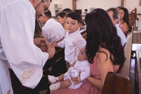 padre abençoando bebe durante batizado nossa senhora de fatima brasilia df registrado pela fotógrafa Letícia Leticia Franco em brasília brasilia df'