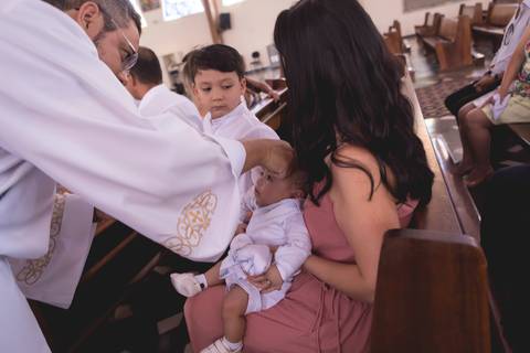 padre abençoando bebe durante batizado nossa senhora de fatima brasilia df registrado pela fotógrafa Letícia Leticia Franco em brasília brasilia df'