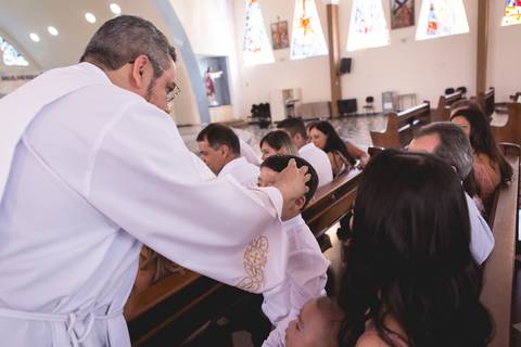 padre abençoando criança durante batizado nossa senhora de fatima brasilia df registrado pela fotógrafa Letícia Leticia Franco em brasília brasilia df'