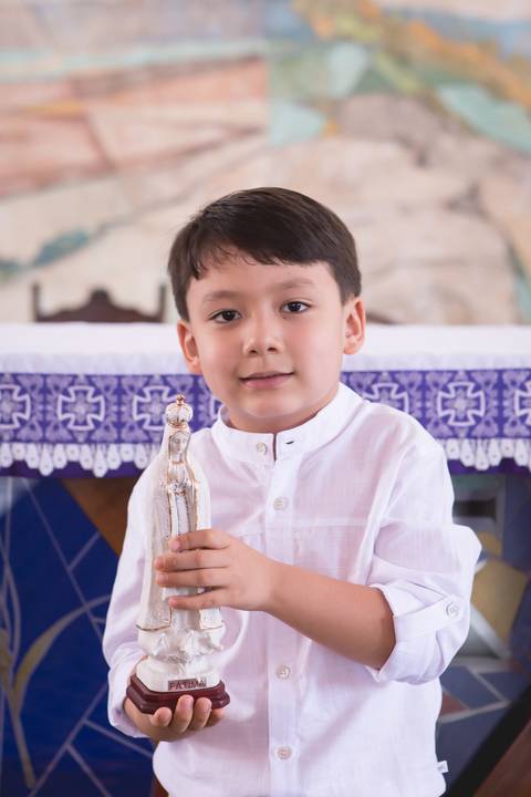 criança batizada segurando imagem de nossa senhora de fátima na igreja brasilia df registrado pela fotógrafa Letícia Leticia Franco em brasília brasilia df'