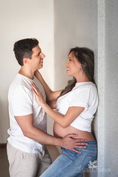 gestante ana luisa ensaio em casa sofa calça jeans fotografada pela fotografa especialista letícia franco em brasilia df ilhas do lago na varanda de casa com o papai eduardo na parede'