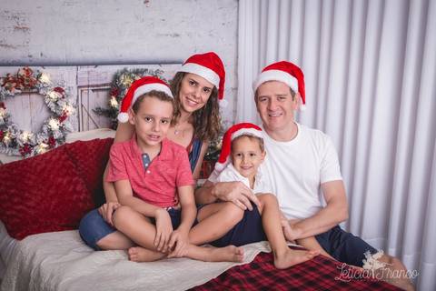 ensaio de natal infantil criança touca de papai noel 2019 brasilia df registrado pela fotógrafa letícia franco quarto do papai noel cama arvore guirlanda lucas e matheus com os pais'