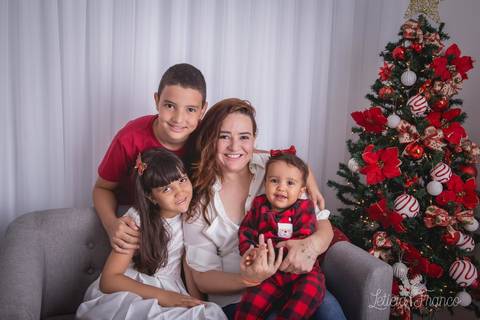 ensaio de natal infantil criança touca de papai noel 2019 brasilia df registrado pela fotógrafa letícia franco casa do papai noel cama arvore guirlanda sala irmãos com mamãe '