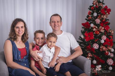 ensaio de natal infantil criança touca de papai noel 2019 brasilia df registrado pela fotógrafa letícia franco casa do papai noel cama arvore guirlanda sala irmãos família'