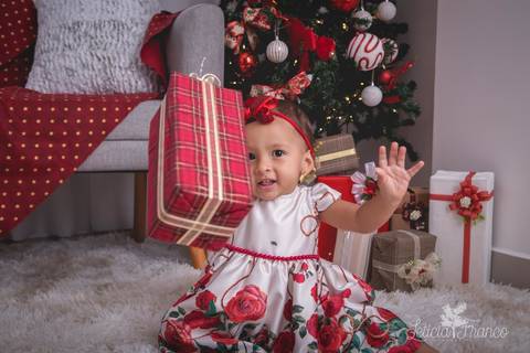 ensaio de natal bebê touca de papai noel 2019 brasilia df registrado pela fotógrafa letícia franco casa do papai noel sala arvore guirlanda roupa de papai noel luisa com presentes'