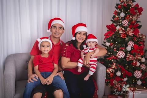 ensaio de natal bebê touca de papai noel 2019 brasilia df registrado pela fotógrafa letícia franco casa do papai noel sala arvore guirlanda roupa de papai noel família no sofá bruno dani julio e théo'