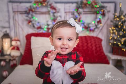 ensaio de natal bebê touca de papai noel 2019 brasilia df registrado pela fotógrafa letícia franco quarto do papai noel cama arvore guirlanda  marina com pijama batendo palma'