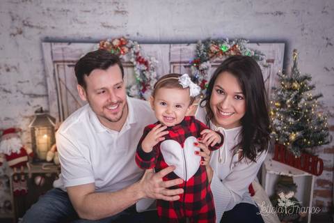 ensaio de natal bebê touca de papai noel 2019 brasilia df registrado pela fotógrafa letícia franco quarto do papai noel cama arvore guirlanda  família bebe marina com pijama e os pais aline e juan'