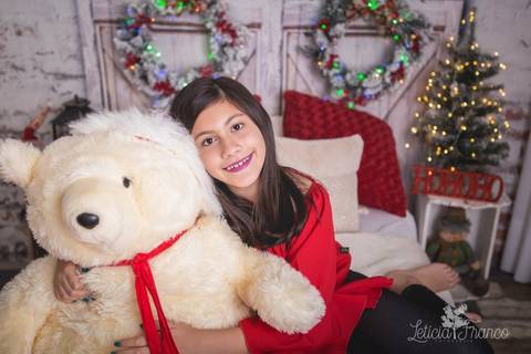 ensaio de natal bebê touca de papai noel 2019 brasilia df registrado pela fotógrafa letícia franco quarto do papai noel cama arvore guirlanda abraçando almofada giovanna touca abraçando urso ursão'