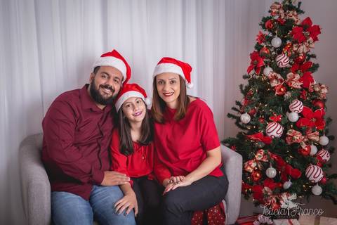 ensaio de natal bebê touca de papai noel 2019 brasilia df registrado pela fotógrafa letícia franco casa do papai noel sala arvore guirlanda roupa de papai noel família pais filha'