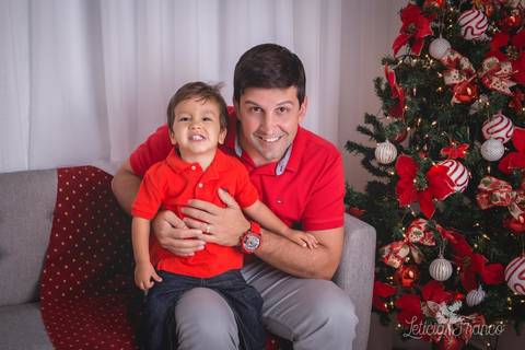 ensaio de natal bebê touca de papai noel 2019 brasilia df registrado pela fotógrafa letícia franco casa do papai noel sala arvore guirlanda roupa de papai noel com papai alfredo vitor sorrindo'