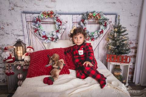 ensaio de natal bebê touca de papai noel 2019 brasilia df registrado pela fotógrafa letícia franco quarto do papai noel cama arvore guirlanda pijama carter's carters maria teresa abraçando ursão urso com mão no joelho'