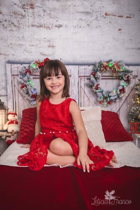 ensaio de natal bebê touca de papai noel 2019 brasilia df registrado pela fotógrafa letícia franco quarto do papai noel cama arvore guirlanda pijama carter's carters maria helena com vestido vermelho fazendo pose'