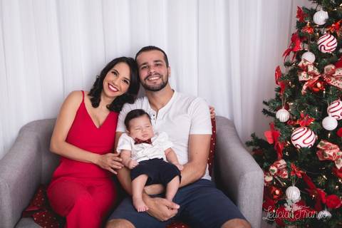 ensaio de natal bebê touca de papai noel 2019 brasilia df registrado pela fotógrafa letícia franco casa do papai noel sala arvore guirlanda roupa de papai noel pequeno romero de 3 meses com gravata borboleta xadrez e a mamãe rayssa com papai bruno'