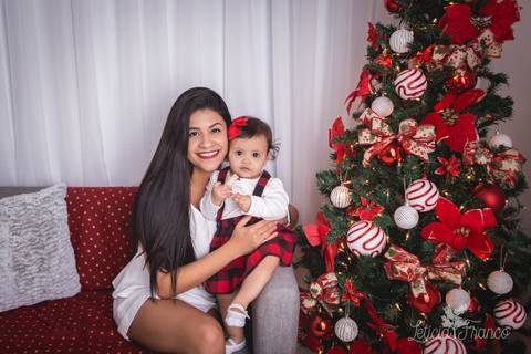 ensaio de natal bebê touca de papai noel 2019 brasilia df registrado pela fotógrafa letícia franco casa do papai noel sala arvore guirlanda roupa de papai noel mamãe e antonella de 8 meses sentadas no sofároupinha da carters carter's súspensório'