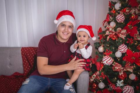 ensaio de natal bebê touca de papai noel 2019 brasilia df registrado pela fotógrafa letícia franco casa do papai noel sala arvore guirlanda roupa de papai noel papai e antonella de 8 meses sentadas no sofároupinha da carters carter's súspensório'