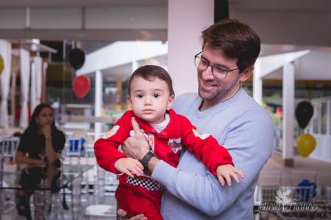 decoração festas criativas carros na happy birthday registrado pela fotógrafa Letícia Leticia Franco em brasília brasilia df com padrinho no colo com macacão de piloto'