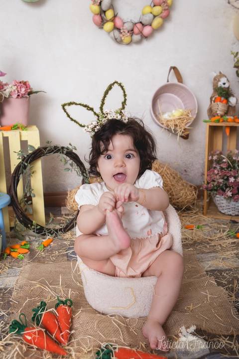 ensaio de páscoa em brasilia leticia franco fotografia df lago sul jardim botanico candy colors coelhos orelha de coelho victoria segurando o pé e sorrindo'