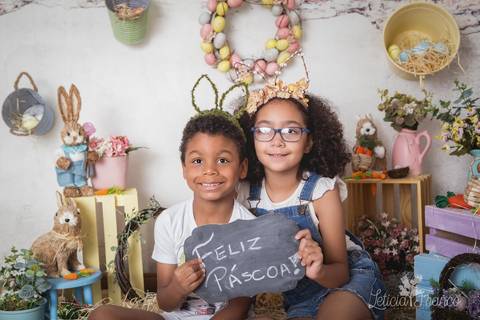 ensaio de páscoa em brasilia leticia franco fotografia df lago sul jardim botanico candy colors coelhos orelha de coelho augusto e clarice segurando a placa de feliz pásco'