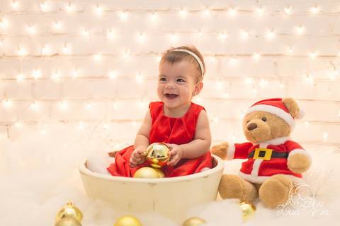 bebe rindo com ursinho de papail noel ensaio de natal com luzes atrás acompanhamento brasília brasilia'