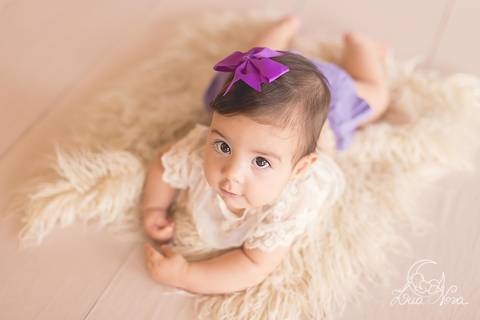 bebê com roupinha de renda, deitado de bruços e lilás ensaio de 6 meses acompanhamento brasília brasilia'