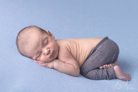 pose do bumbum pra cima com bebê recém nascido e calça cinza e fundo azul newborn brasilia'