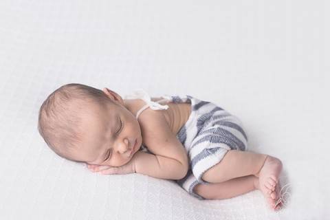 bebe fazendo pose de lado fundo branco com macacão listrado de branco e cinza brasilia preço'